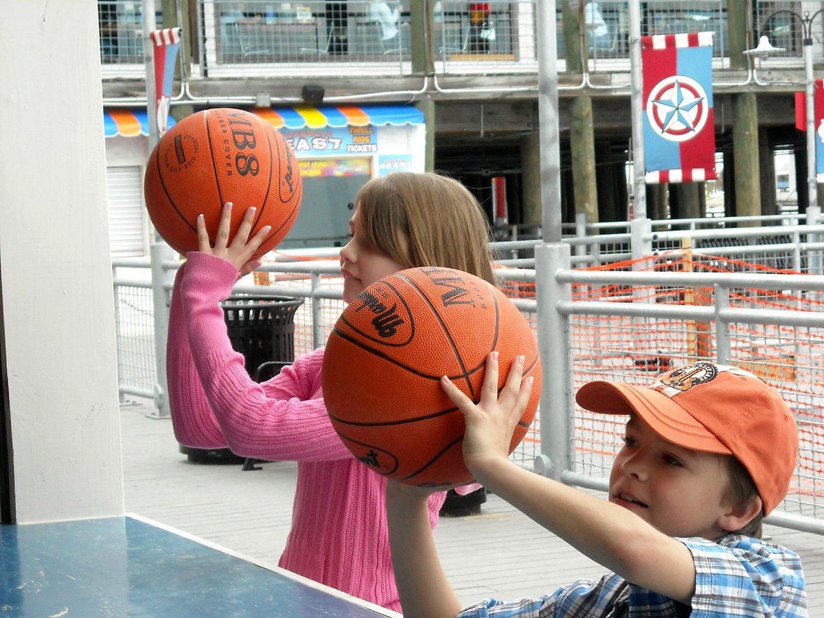 kids playing basketball game on boardwalk