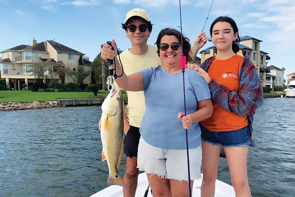 Showing a family holding a caught fish while out on a boat.
